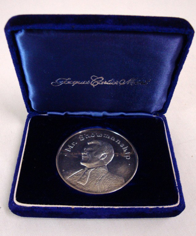 LIBERACE'S MR SHOWMANSHIP MEDAL: "Mr. Showmanship" medal. A portrait of Liberace on one side. Reverse side is a depiction of Liberace's famous logo autograph with piano. In original case, marked Jacques Cartier Mint. This medal was p