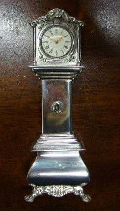 STERLING SILVER MINIATURE - TALL CASE CLOCK: Marked Holland, HH, with 3 hallmarks. This clock and all the sterling miniatures were used to create a rusic room by Liberace for Christmas. The Oak "room" with wainscoting and a stained glass window