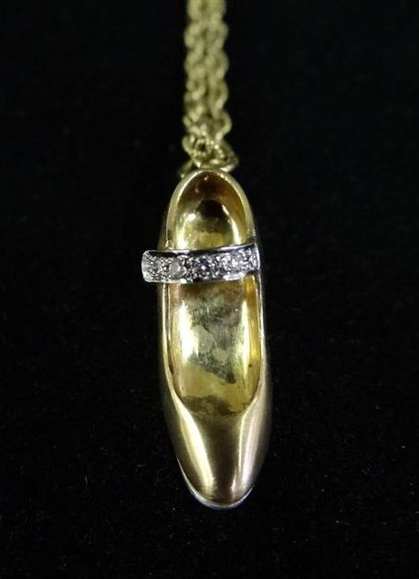 LIBERACE'S 14K DANCING SHOE ON A 14K CHAIN: A 14K yellow gold dancing shoe with a 14K white gold tap and heel bottom. Inscribed Liberace at the underside of shoe. Pave diamond shoe strap on 14K gold Florentine open link chain. *A gift to Libera