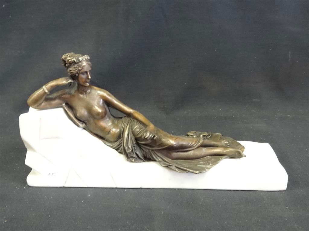 BRONZE RECLINING SEMI-NUDE FIGURE: Figure of a woman on a white marble "chaise lounge" base. 6"H. 11 1/4"L. 3 1/2" W.