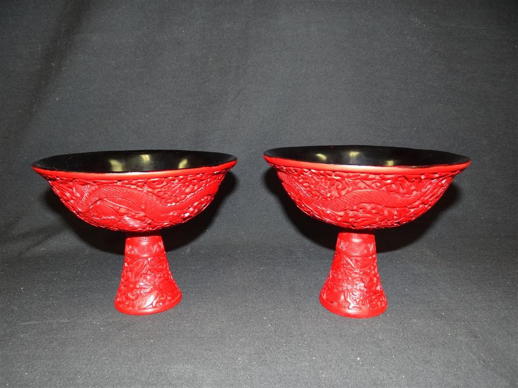 PAIR OF CARVED CINNABAR STEM CUPS: Depicting five claw dragons after a flaming pearl. 6-1/4” wide x 5-1/4” high