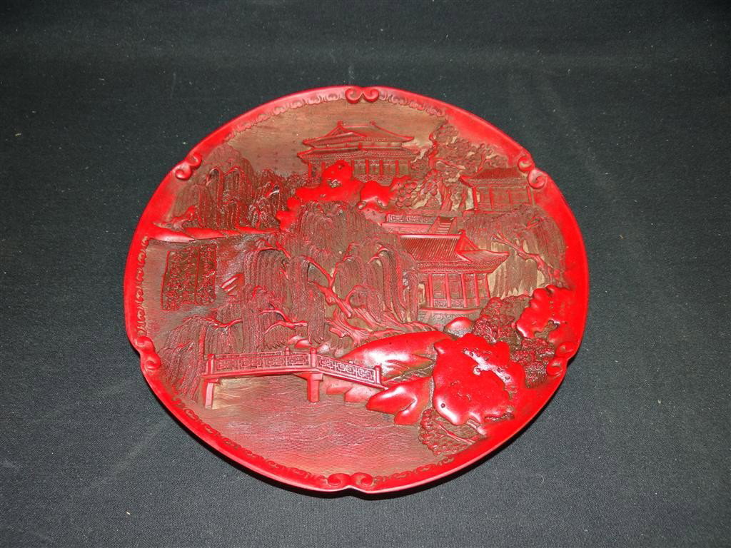 CHINESE CINNABAR PLATE: cinnabar carved plate with high relief decoration; 9.75in. D.