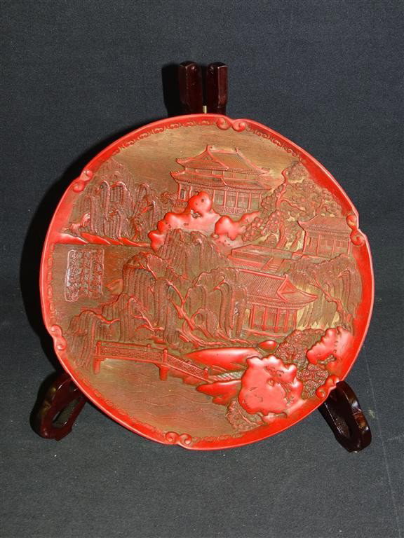 CHINESE CINNABAR PLATE: cinnabar carved plate with high relief decoration; 9.75in. D.