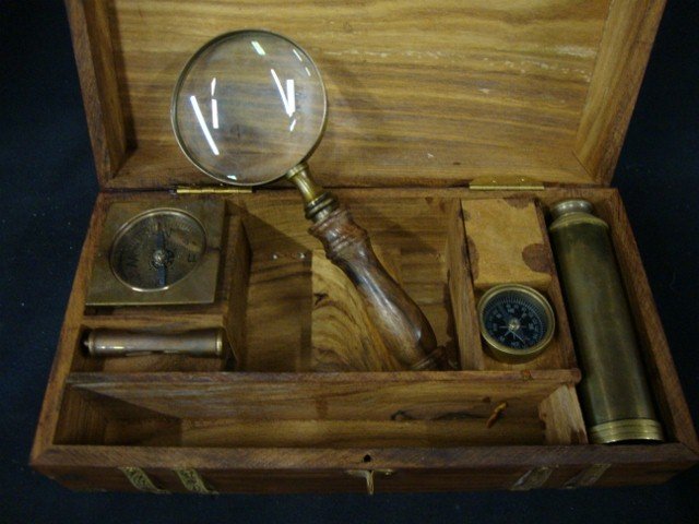 Nautical Instrument Box: Brass bound chest opens to reveal an adjustable brass telescope; two compasses; a magnifying glass with a wooden handle and a small hour glass that could be worn as a pendant or attached to a hook on 