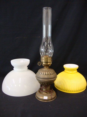 Brass Oil Lamp and Two Shades: A brass oil lamp , turn of the century. Included in the lot are two lamp shades, one milk opalescent glass and one yellow cased ribbed.21 1./2" to shade top. 11 3/4"W and 10"W.