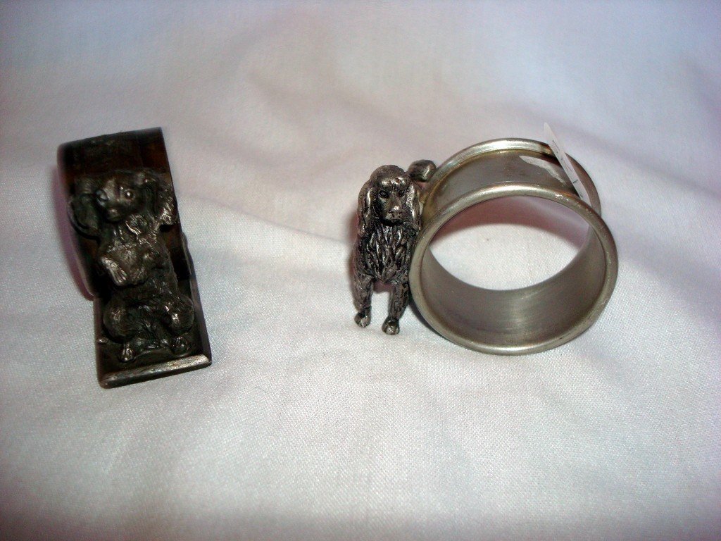 Two Napkin Rings With Dog Figures: One is Reed and Barton, signed and numbered 1425, a small dog on hind legs; the other is a poodle figure and is marked Pewter