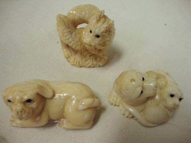 Three Carved Ivory Netsukes: All with signatures. One a dragon, one a recumbent dog and one intertwining serpent and cub. 2" long; 1-1/2" high; 1-1/2" long