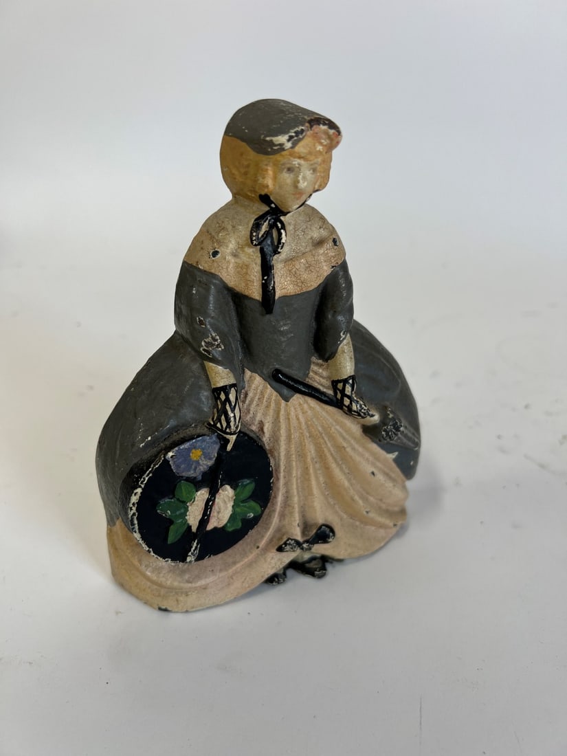 Cast Iron Door Stop A Girl With Hat Box: 6 3/4"H Woman in hoop skirt with parasol and hat box . Perhaps Albany Foundry, Marked 30 at the backside.