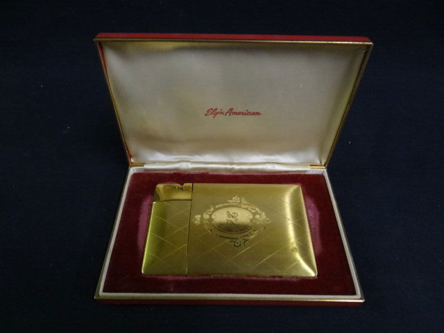 Paula Klaw's Cigarette Holder with Lighter: One gold cigarette holder and lighter combination with Paula Klaw's initials (PK) engraved on the front, made in the USA by Elgin American. In a hard red box with a red velvet lining.
