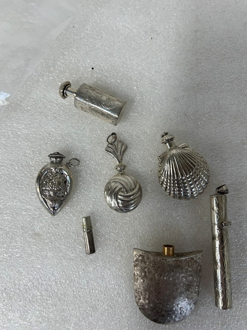 Six Sterling Silver Scent Bottles: Shell shaped, six sided bottle, cylinder shaped, beaded design, floral design and swirl design. All but one marked 925. 1 3/4" to 3"
