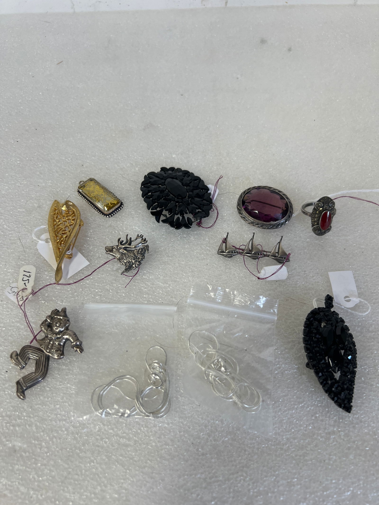 Collector or Dealer's Lot of Vintage Jewelry: Sterling boats pin, sterling deer pin, black onyx beaded pin, sterling jointed clown pin, bronze gold toned filigreed pin, 2 sterling link chains,a sterling, marcasite and carnelian ring. an amethyst