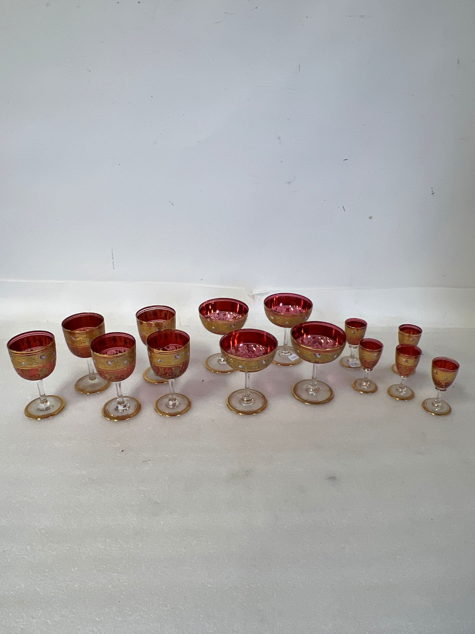 Best Quality Enameled Cranbetty Stemware: Five Cordials,5 Wines,4 Champagnes. With Gilt bands and enameled and gilt decorations. (14 pcs in the lot)