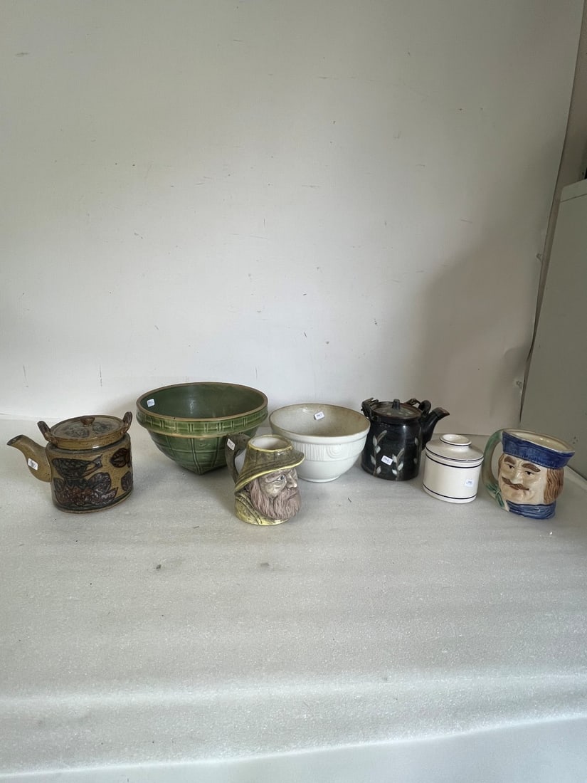 Dealer or Collectors Lot of Antiques. (7): Two mugs, a covered sugar, two stoneware teapots and two bowls, one green with an unidentified mark at the bottom, a 9 in a shield and a white bowl marked Hall. (Some lines through Hallmark) Seven