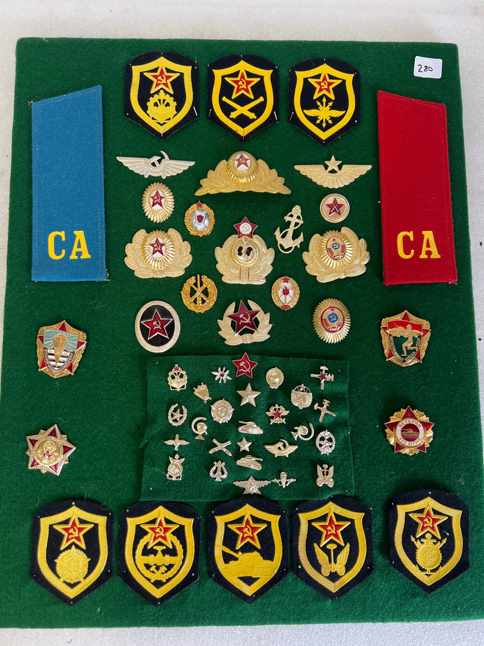 Vintage Lot of Russian Patches/Medals/Pins: Lot includes various Soviet Russian military patches, pins, and badges from the Cold War era on board. Overall size is 20”H by 16”W. 10 patches, and about 45 pins/medals.
