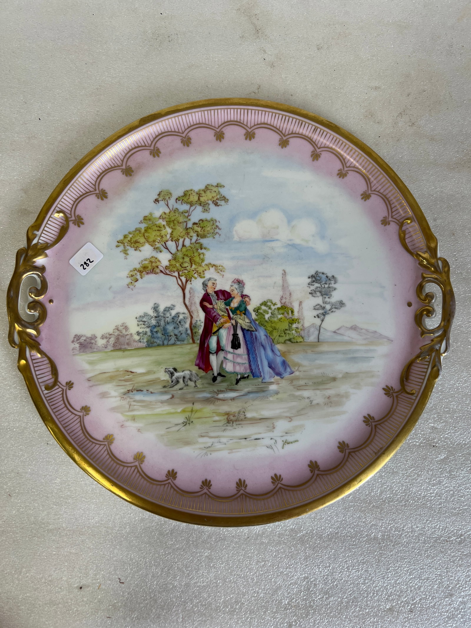 Vintage KPM Serving Tray: decorative porcelain plate features a hand-painted scene of a courting couple in a pastoral setting. Signed J Korwon. 15”In diameter. Marked KPM at the underside.