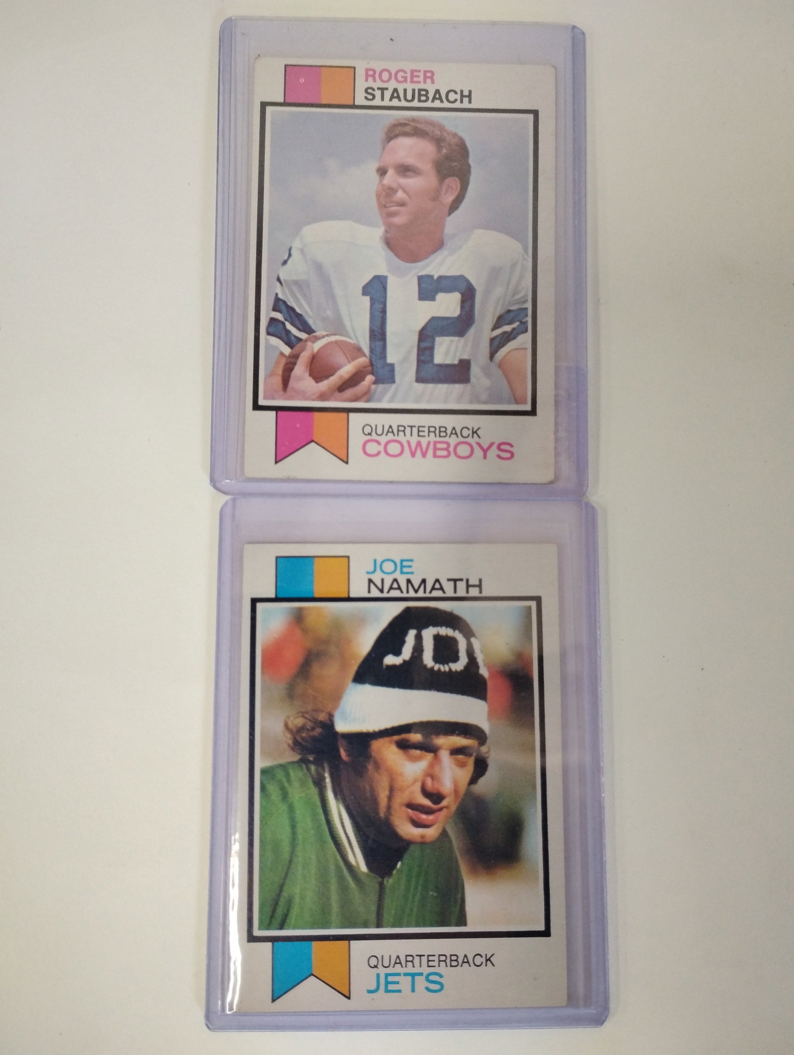 Namath/Staubach Topps Cards (2): 1973 Topps Football cards of Joe Namath and Roger Staubach. In protective Sleeve. Two in the lot.