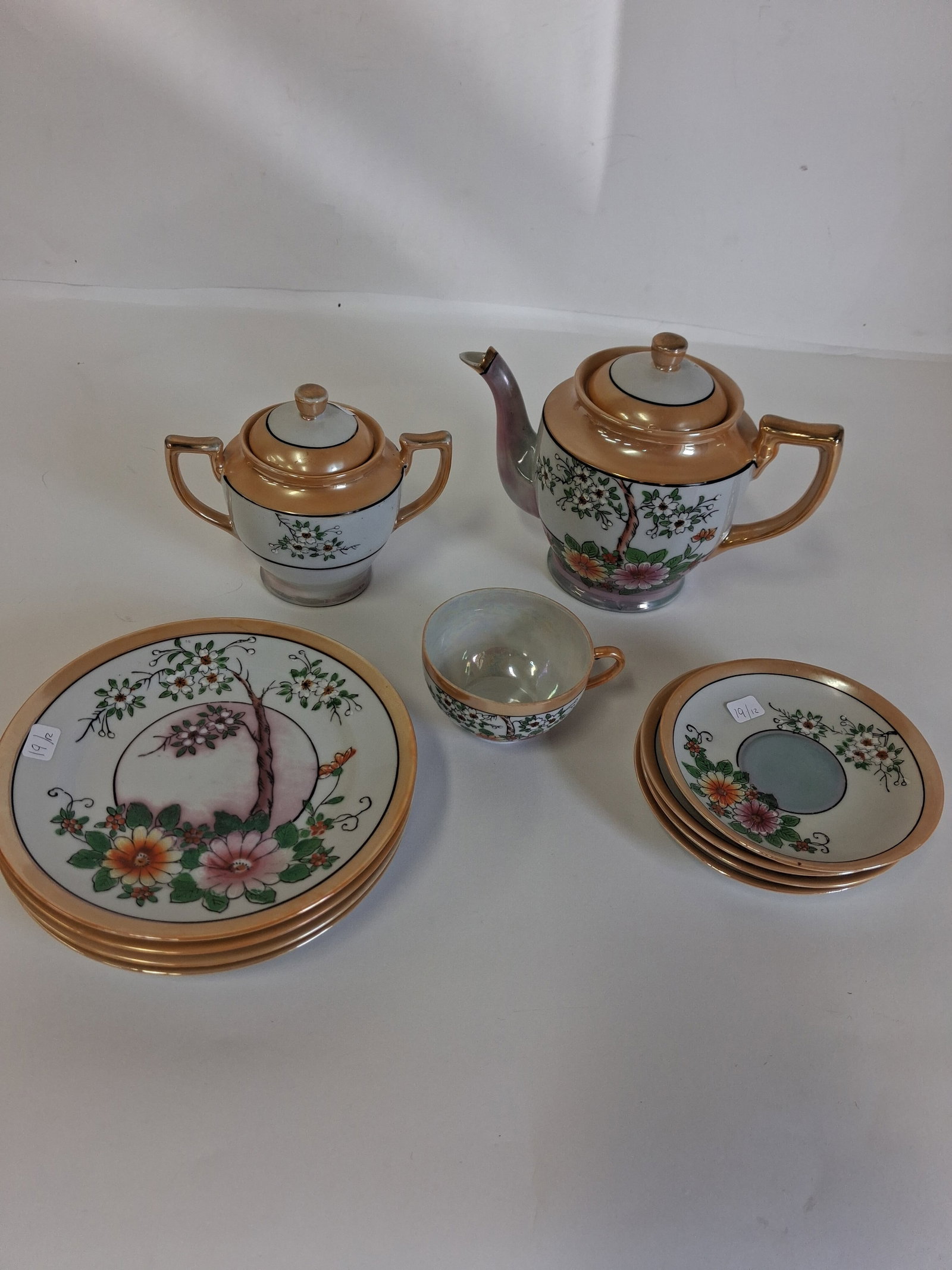 Vintage Hand Painted Japanese Lusterware Ceramic Tea Set (12): 12 pieces in the lot. All marked at the underside "Made in Japan". Lot includes: 5 dessert plates, 4 tea saucers, 1 teacup, 1 sugar dish and a Tea pot. As pictured.