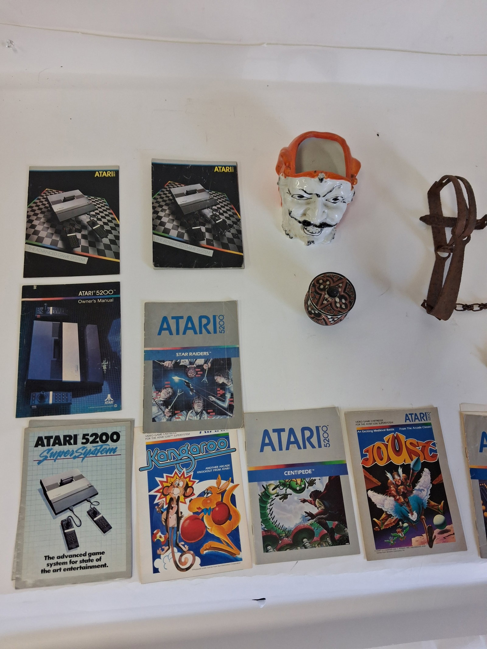 Atari Manuals (13) and Collector's Pottery and Cast Iron: 13 Atari booklets, a pottery devil planter, a pottery covered jar, and a primitive cast iron item as pictured.