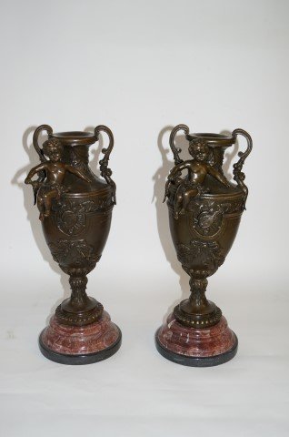 Pair Bronze and Marble Mantle Garnitures: Bronze and marble mantle garnitures, the rouge marble base gives rise to cherub mounted floral decorated bronze vases. 17"H.