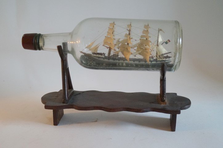 Handmade Ship's Model in a Bottle: Intricately crafted ship's model in a bottle. Wood stand; 8in. H. x 11in. W.