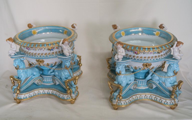 Pr. European Porcelain Centerpieces: Spectacular centerpieces. Hand painted. The mythological animal figures with cherubs atop support the cachepots at the top. Blue crossed sword marks on an affixed label. 15"H. x 14"W. x 14"D.