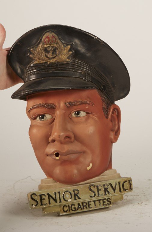 Senior Service Cigarettes Wall Plaque: Painted plaster. Depicts a British Naval officer with mouth meant to hold a cigarette. London. A Leonardene Product for Curson Enterprises Ltd. ; 14" x 10 1/2"
