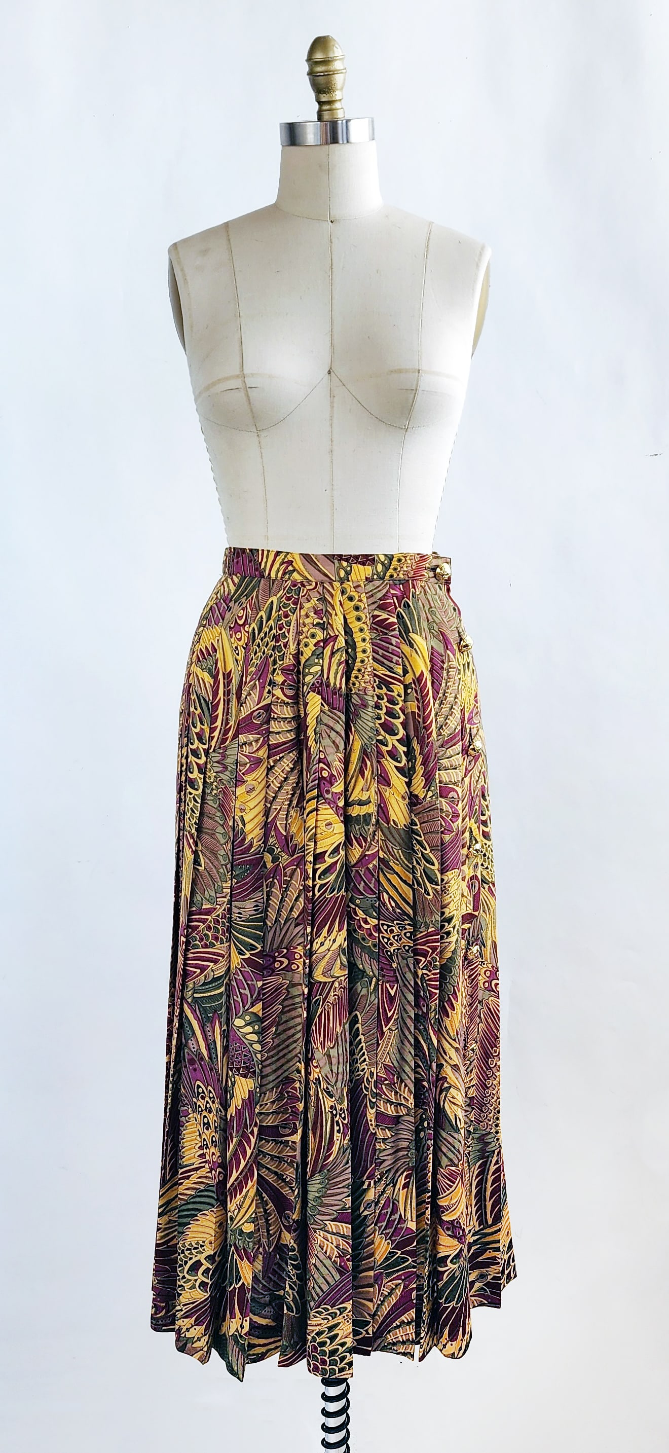 Salvatore Ferragamo Multicolor Floral/ Feather Print Wool Pleated Skirt, c. 1990s: Salvatore Ferragamo autumn colors stylized feather or floral print wool pleated skirt with gold tone buttons, ca. 1990s. Made in Italy. Size label 12, approximately modern size US 8. Provenance: Estat