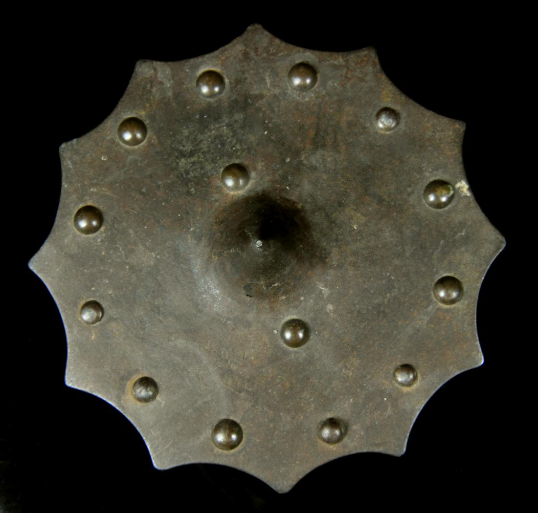 A PAULDRON FROM GOTHIC ARMOUR, EUROPE, 15TH-16TH C.: Origin: Western Europe. Dimensions: diameter - 13,2 cm. Weight - 152 g. Round iron pauldron with edges cut in semicircles, with 12 brass rosettes going around and two brass rosettes near the peak, whi