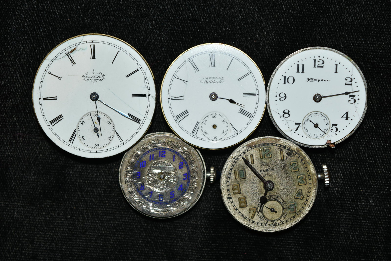 Box lot of five antique pocket watch works. Porcelain: Box lot of five antique pocket watch works. Porcelain and metal dials. Largest is 1 1/4" . One has very fancy dial, with sapphire insert on winder, 15 jewel, Larmin marked W. Co. Swiss. Two Elgins. Am