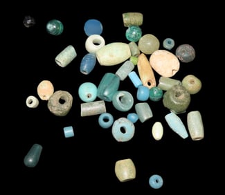 Ancient Roman and Egyptian glass, faience, and carved stone beads in shades of blue and green,