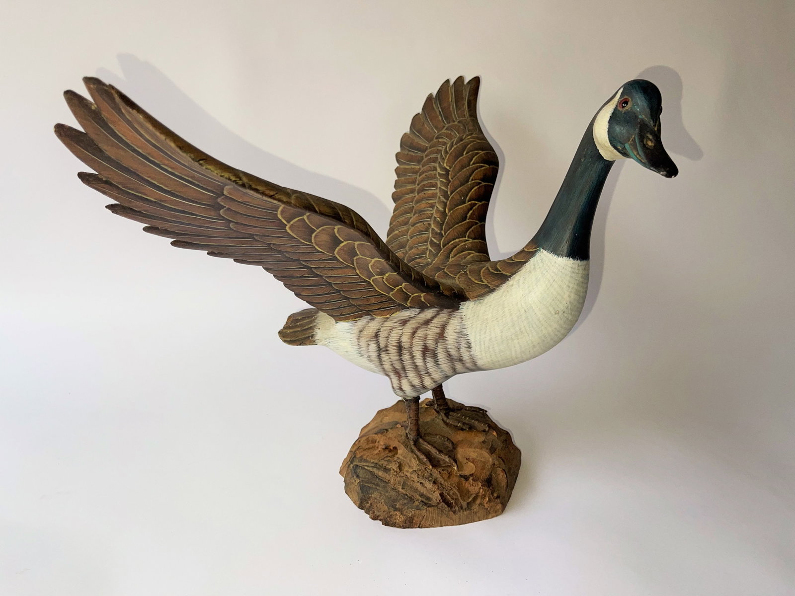 CARVED AND PAINTED GOOSE WITH OUTSPREAD WINGS: CARVED AND PAINTED GOOSE WITH OUTSPREAD WINGS ON WOODEN BASE. 12.5" TALL X 18" WIDE. OVERALL GOOD CONDITION , SOME VERY MINOR CHIPS