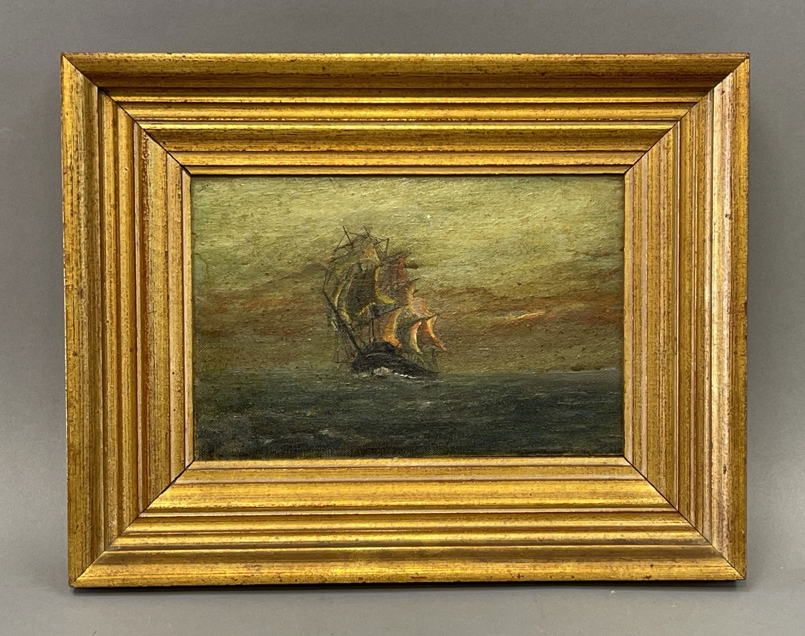 19TH CENTURY MARINE OIL ON BOARD: 19TH CENTURY MARINE OIL ON BOARD. SHIP UNDER SAIL AT SUNSET. SIGNED BY ARTIST. UNABLE TO READ. IN GOLD FRAME. SIZE: SS: 9” WIDE X 6.5 HIGH. OS: 13.25 WIDE X 10.5. GOOD CONDITION.