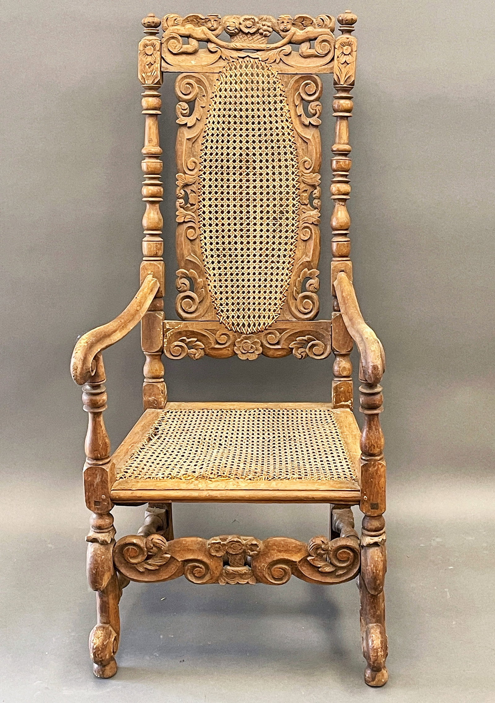 CARVED AND SCROLL CANE ARMCHAIR WITH SCROLLED LEGS: CARVED AND SCROLL CANE ARMCHAIR WITH SCROLLED LEGS,CARVED SUPPORTS CALLED PUTTI CREST , PEGGED , C. 1680-1700 OLD CANE SEAT 58" X 28" X 17"