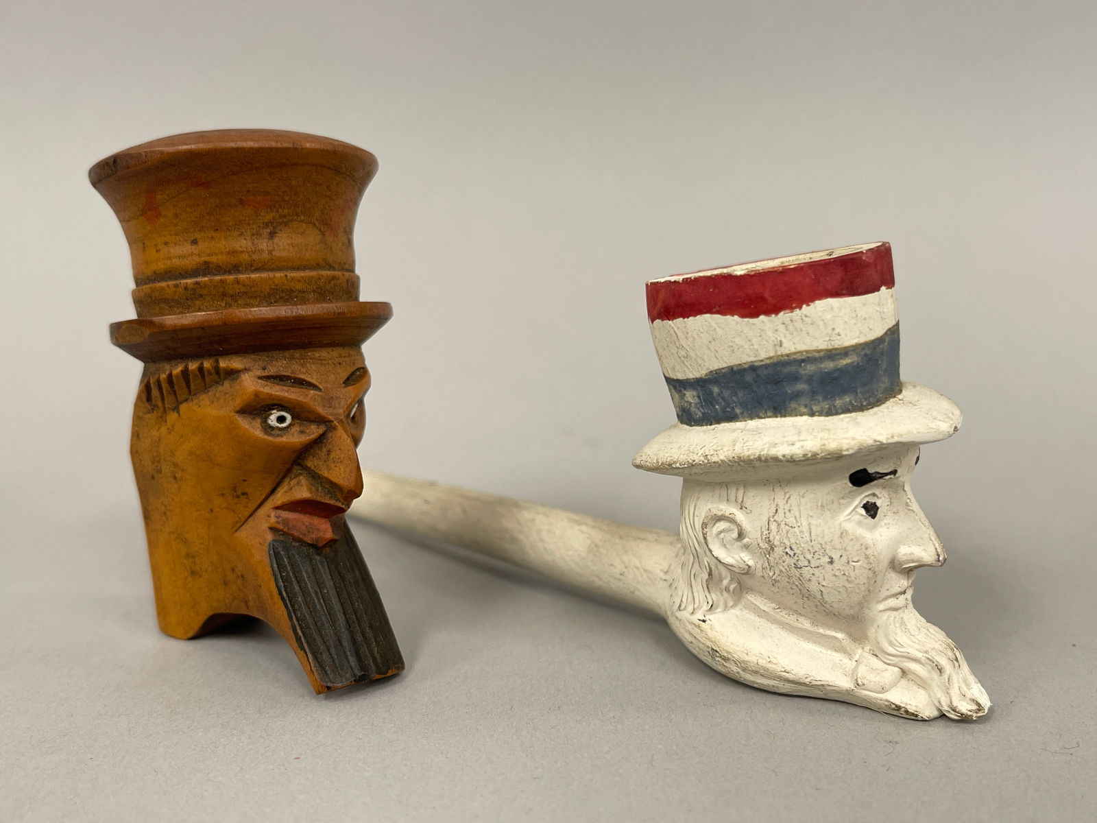 UNCLE SAM PIPES: UNCLE SAM PIPES Lot of 2, carved wood & original painted clay, late 19th C, excellent condition.