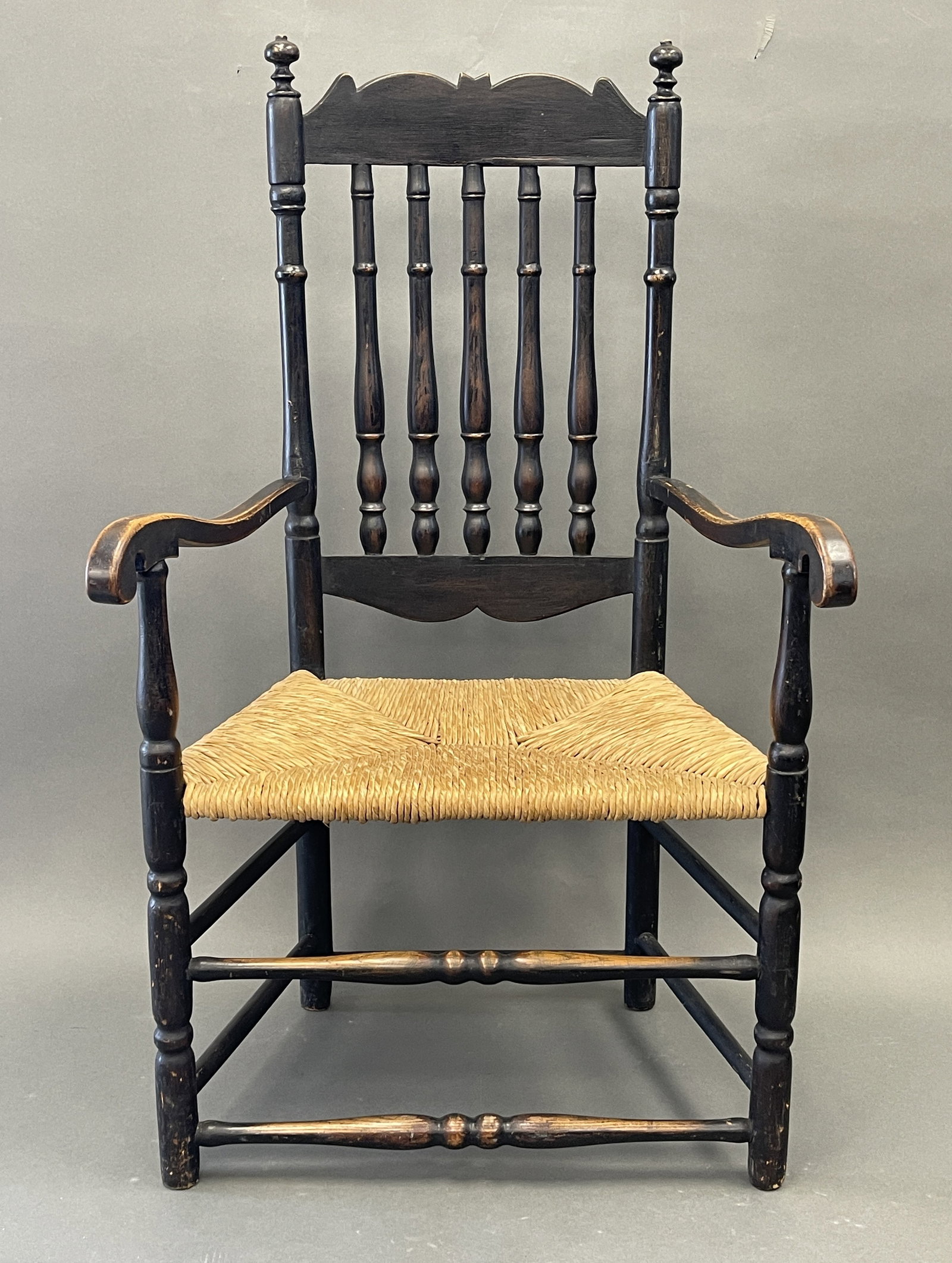 18TH C DEERFIELD MA BANNISTER BACK ARMCHAIR: 18TH C DEERFIELD MA BANNISTER BACK ARM CHAIR IN OLD BLACK OLD BLACK SMITH REPAIR ON BACK OF CREST C1740 43" X 25" X 17"S