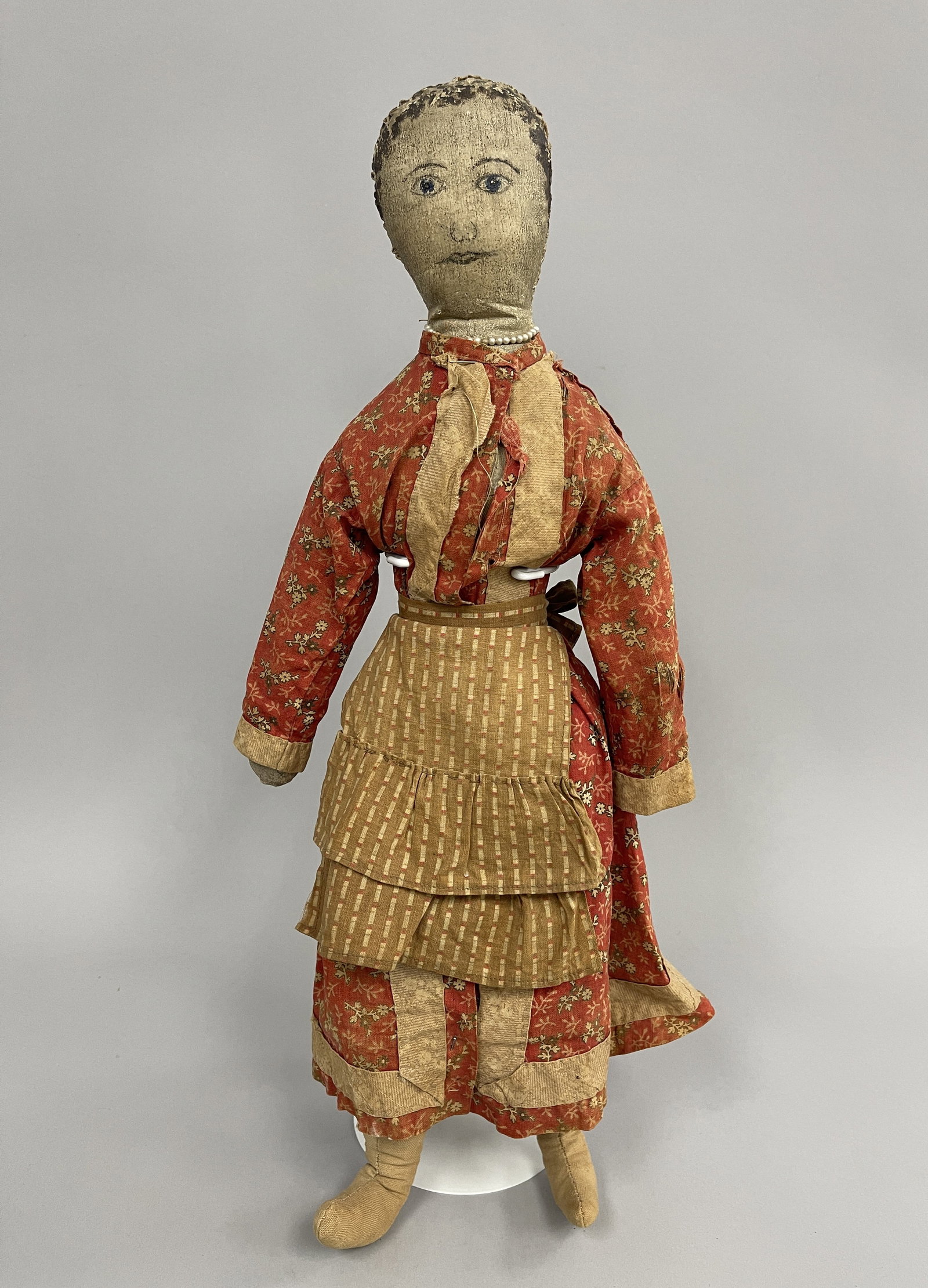 LEATHER GIRL RAG DOLL: LEATHER GIRL RAG DOLL 19TH C, LEATHER TORSO, FACE & HANDS, PAINTED FACE, RED DRESS & TAN APRON, EXCELLENT CONDITION.
