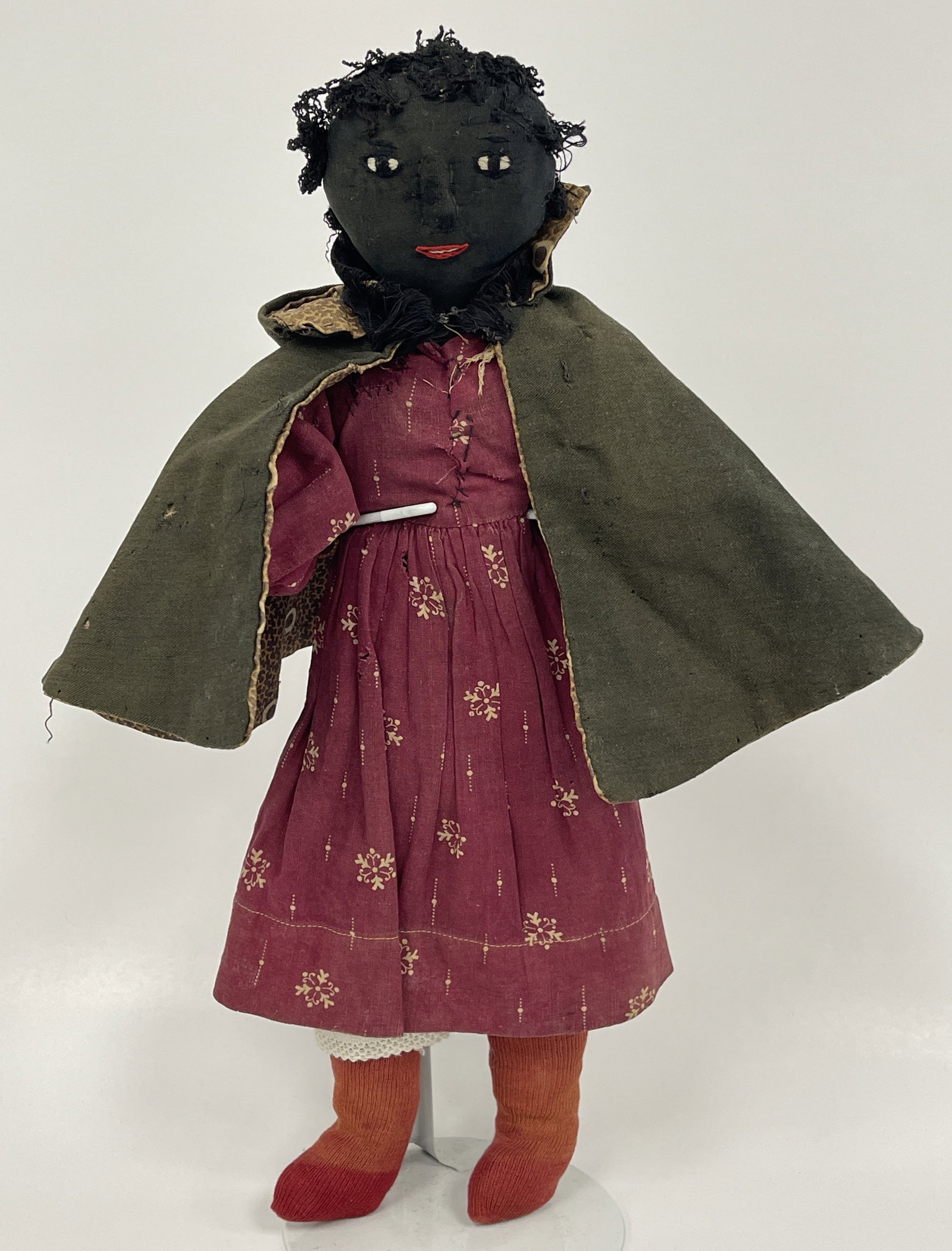 EARLY BLACK RAG DOLL: EARLY BLACK RAG DOLL 19TH C, EMBROIDERED FACE, CRANBERRY DRESS, BLACK CLOAK