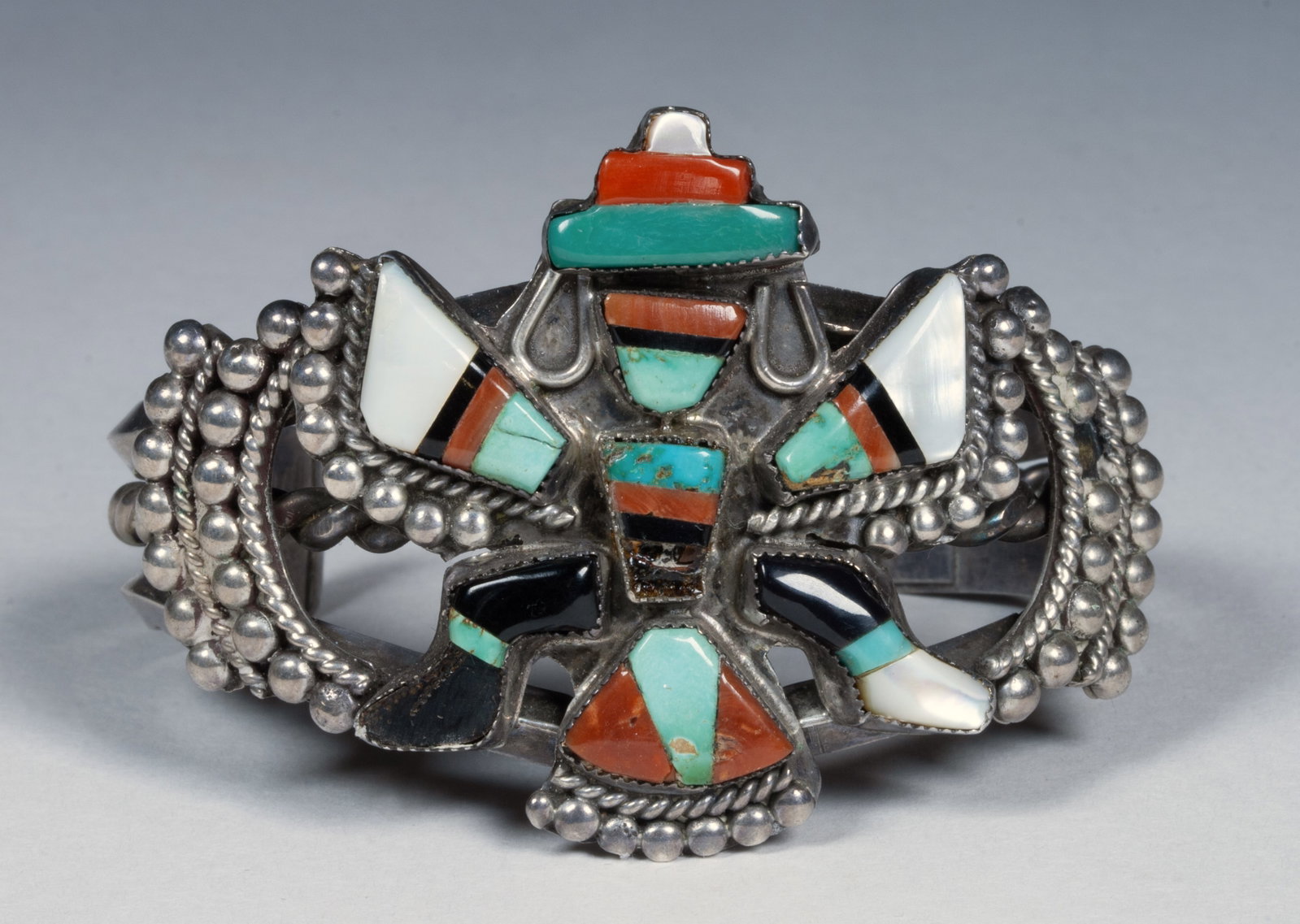 Zuni Knifewing Silver Inlay Bracelet - 1940s Native American: Zuni silver and stone inlay bracelet. Unsigned. Decorated with rows of sumptuous silver beads surrounding a Knifewing figure inlaid with turquoise, coral, jet, and mother of pearl. Tests as sterling. 