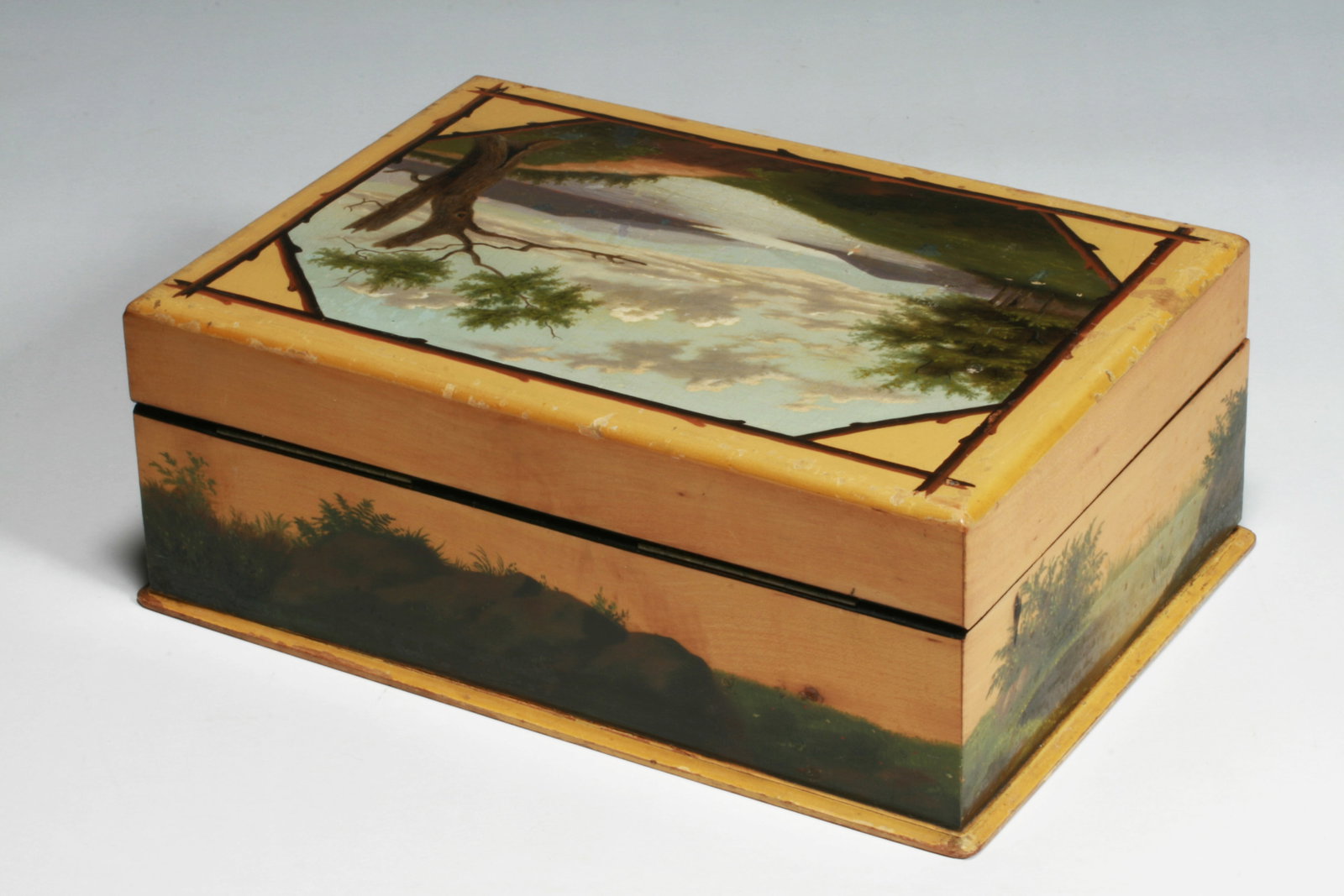 American Folk Art Hudson River School Painting on a Wooden Box - 1870: A good American folk art painted box. Circa 1870. The top painted with an expansive Hudson River scene bordered by painted Adirondack wooden branches on a mustard background. All four sides are also p