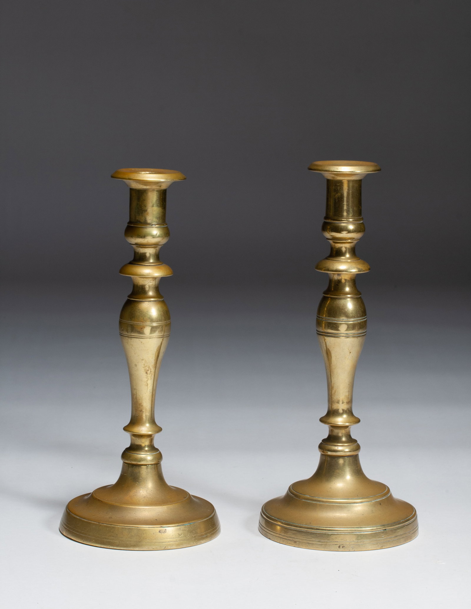 Early Turned-Brass Candlesticks - 18th / 19th Century: A fine and early pair of heavy brass candlesticks. 18th-19th century. Possibly of Early American origin. Classic form with turned construction and large screw-socket bases (the stems screw into the ba