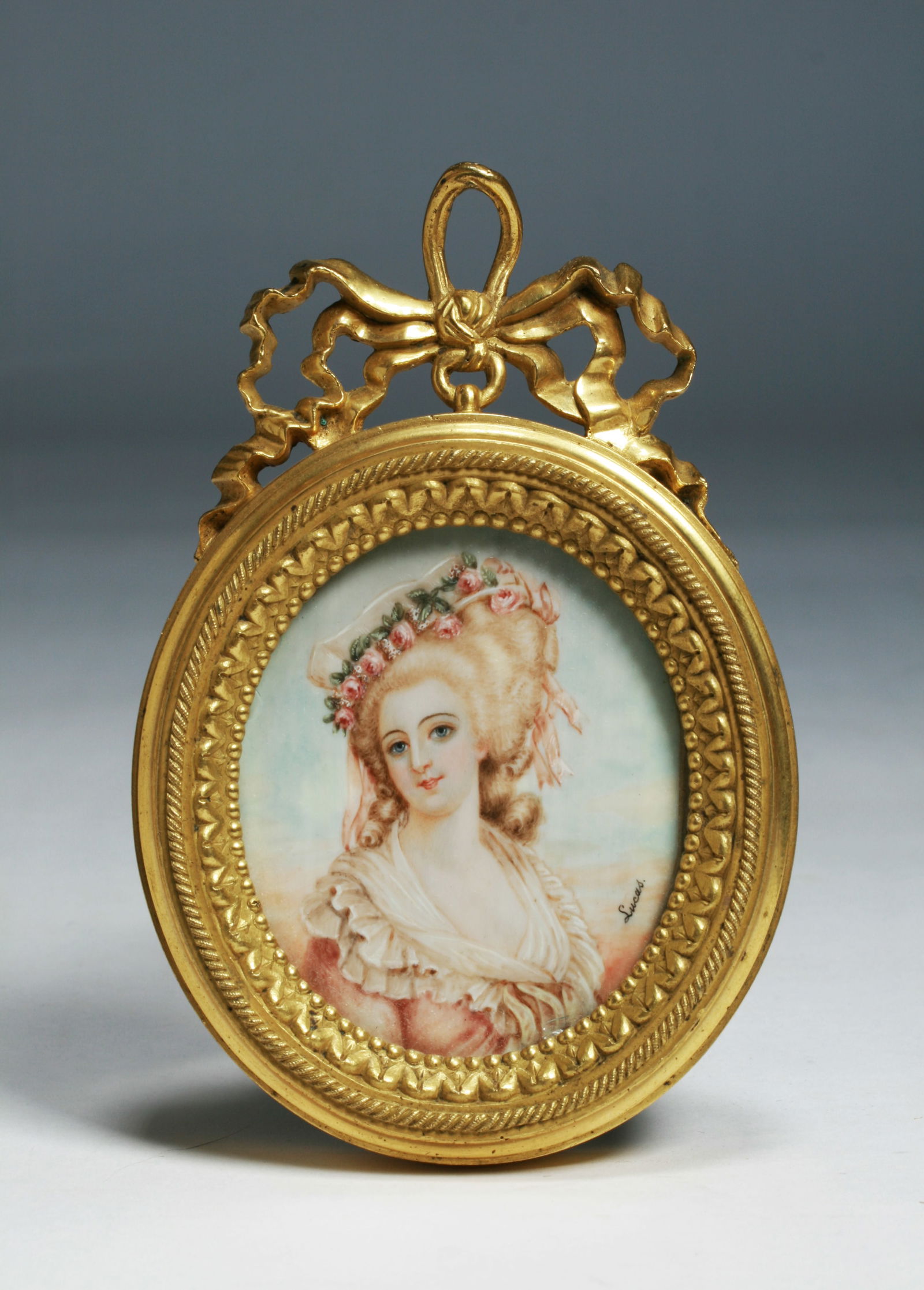 French Miniature Painting in a NeoClassical Bronze Frame: A miniature painting of a woman. French, early 20th century. Framed in a heavy bronze oval frame. The painting is signed at the lower right, "Lucas". The frame is quite heavy and this piece may have