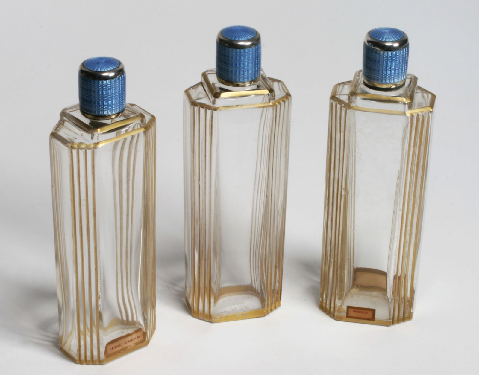 Three French Art Deco Glass Perfume Bottles - Silver & Enamel Tops: Set of three elegant French Art Deco silver & enameled glass perfume bottles. Designed with rectangular panels and gilded accents. The top covers are made of silver with a beautiful translucent light