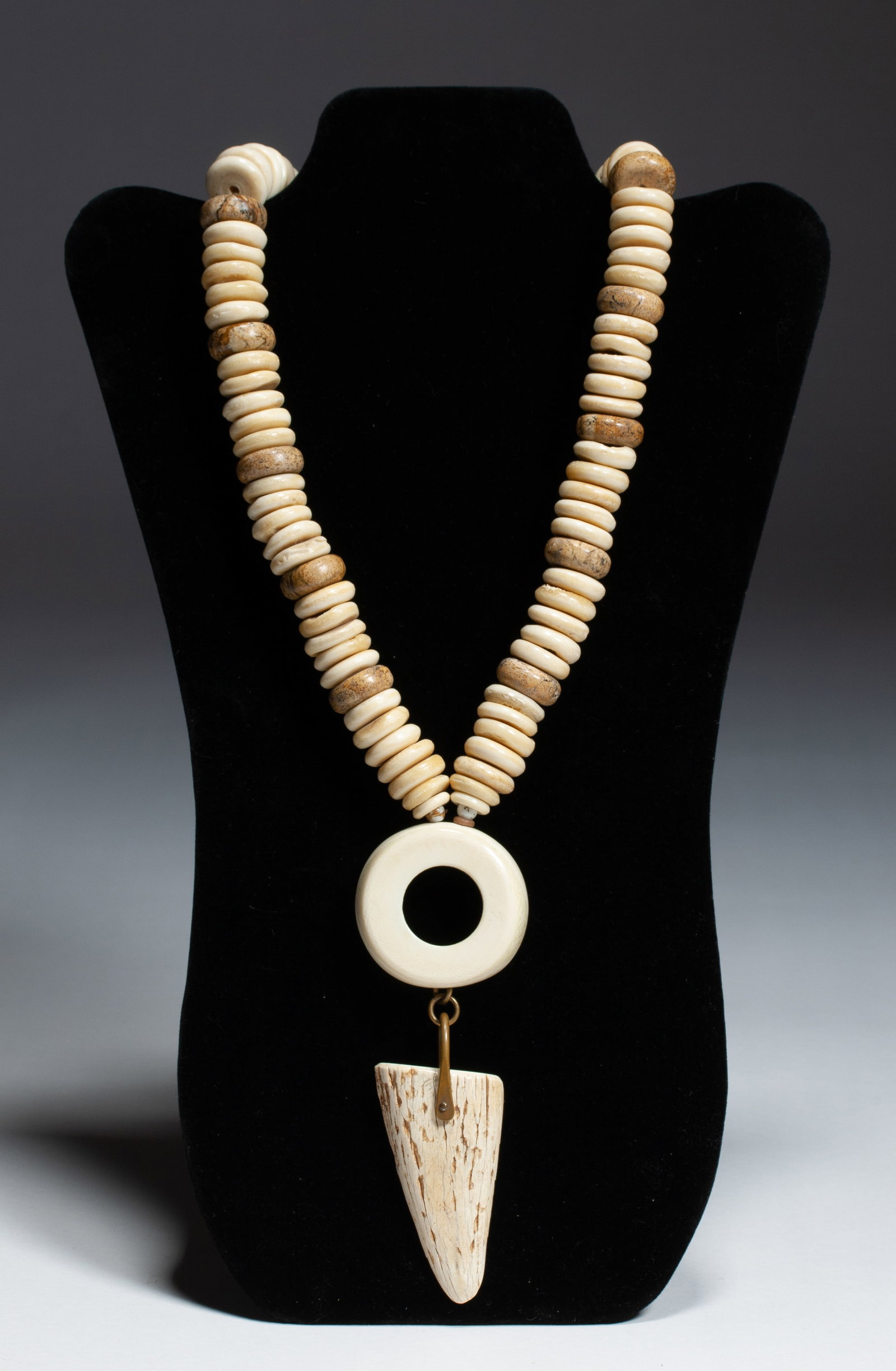 New York Designer Necklace by David Navarro 1970's: Stunning modernist statement necklace by well-known American jewelry designer, David Navarro (1928 - 2015). Made of large bone and stone beads with a brass pendent holder and his signature circle & po