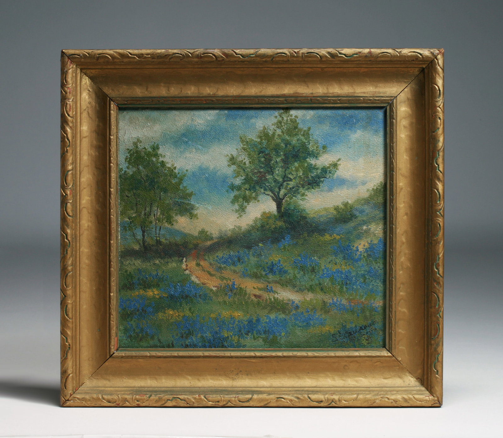 Old Texas Impressionist Painting - Bluebonnets - Signed: An old Texas landscape painting of bluebonnets, trees and a road. The painting is signed, lower left, please see the photographs. Unidentified artist. Oil on academy board. Mounted in the original gol