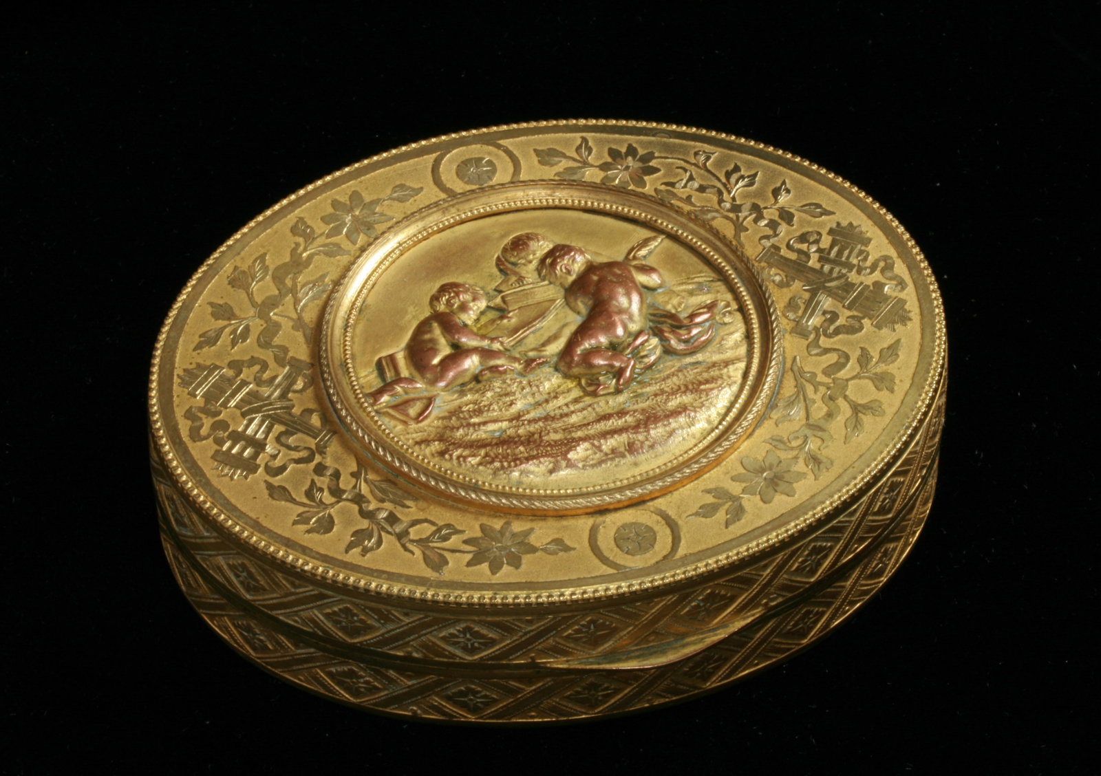 Antique French Gilded Box with Cherubs: Antique French powder or jewel box decorated with etched Neoclassical designs and a center copper-bronze sculptural plaque of a Cherubs reading and writing. The interior is lined in velvet. Circa 1900