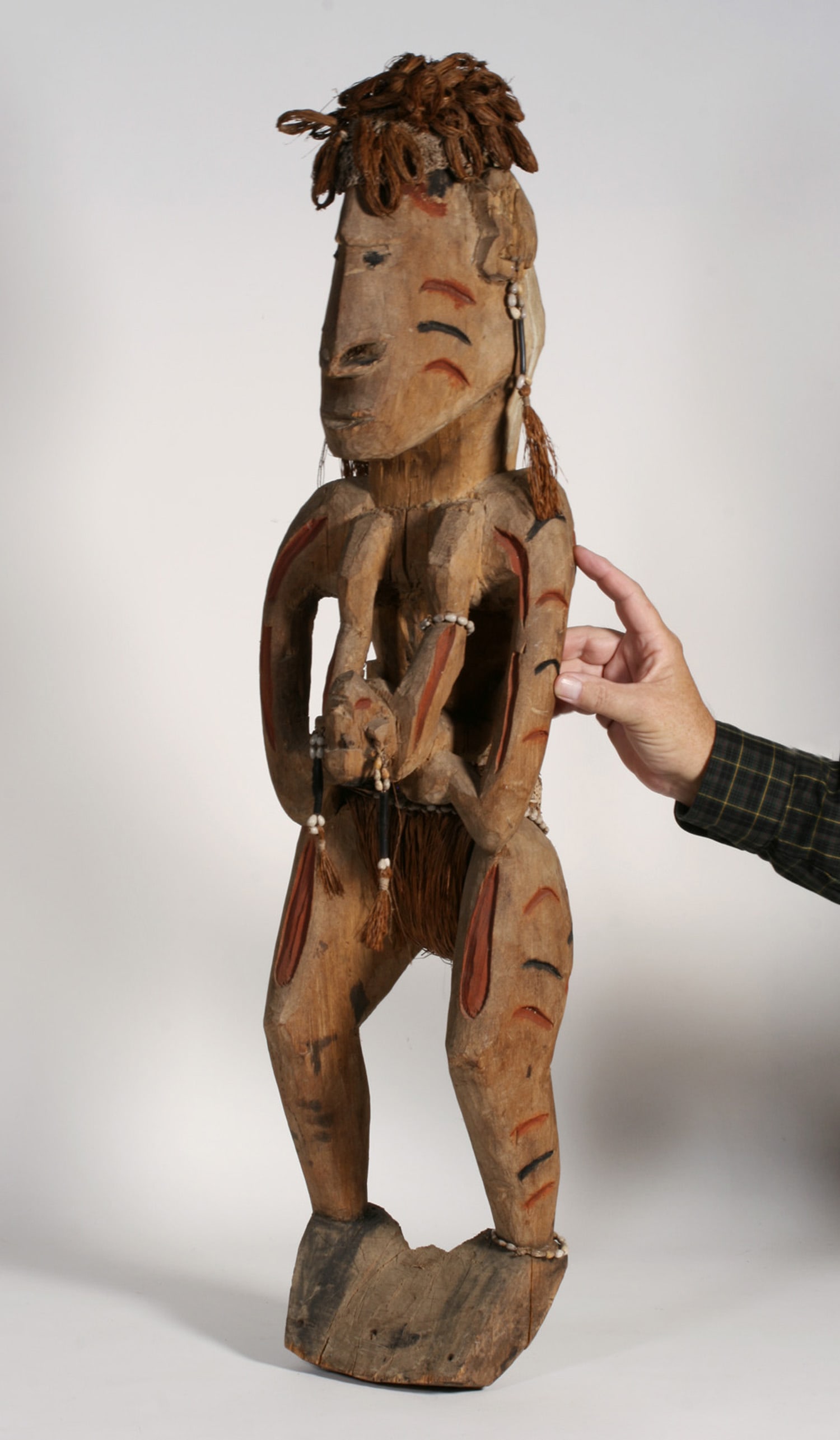 Large Asmat Tribal House Figure - PNG Papua New Guinea: Large Asmat carved and painted wood figural sculpture, decorated with a woven hat, belt and ear ornaments. Irian Jaya - Papua New Guinea. Early to mid 20th century. Depicts two figures, the small figu