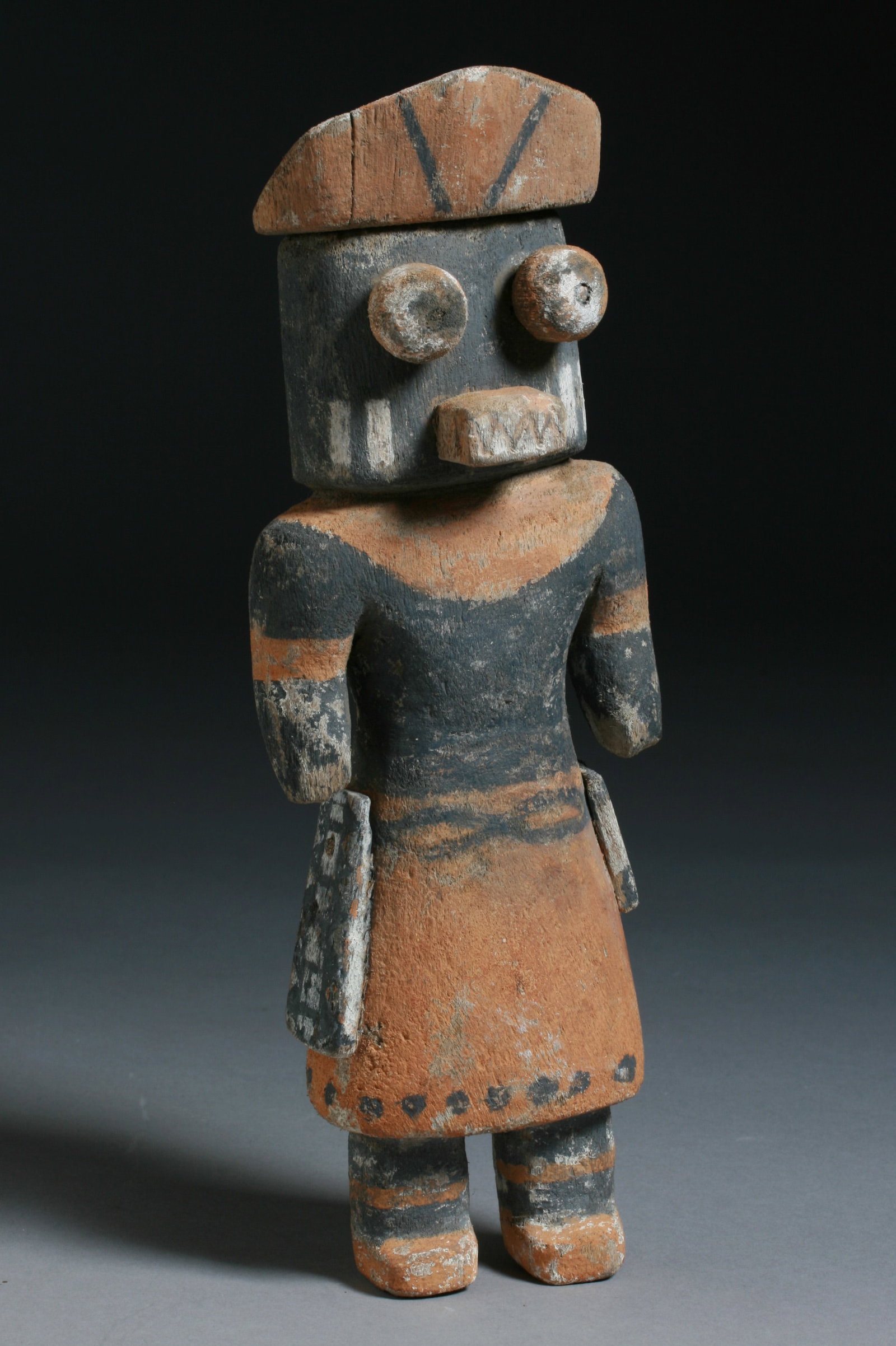 Old Hopi Kachina Doll - Native American: A good Hopi Kachina doll wearing a dance mask, kilt and sash. Protruding eyes and a fanged mouth. Early 20th century. The eyes, mouth hat and sashes are separate pieces and the rest is carved from a s