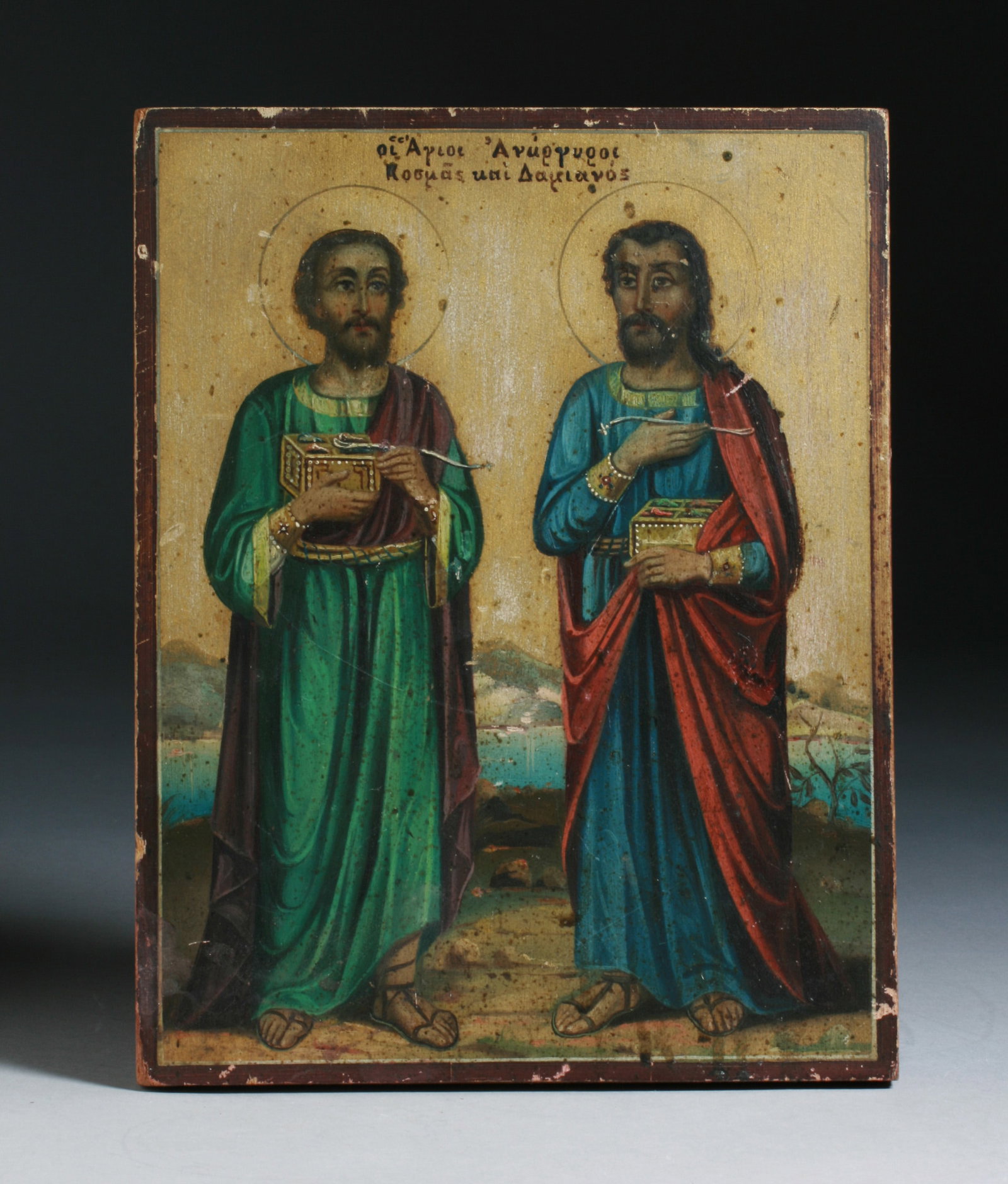 Russian Eastern Orthodox Icon: A Greek or Russian Orthodox painted icon depicting Saints Komas and Damian. Early 20th century. Both Saints holding a box and a spoon, with a gold background. Oil on wood. SIZE : 8 3/4" x 11 1/4" x 3/