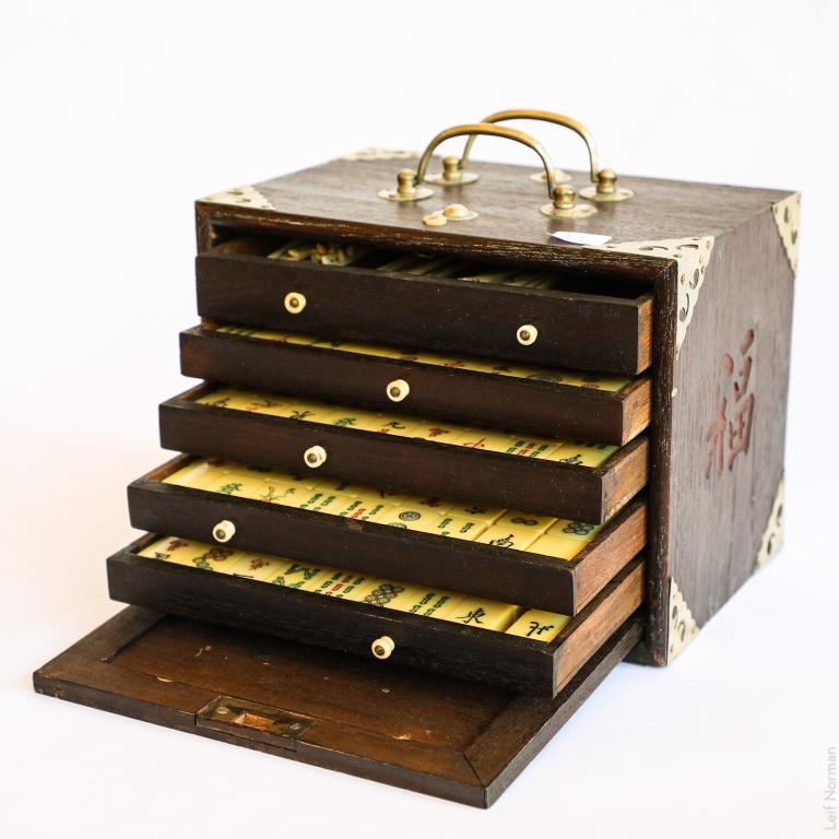 MAH JONG SET: Oriental hardwood box, original brass moldings and bone and French ivory playing pieces. Early 20th century.