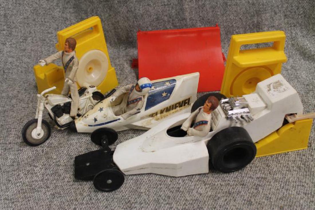 Evel Knievel toy lot: Sky cycle, motor cycle, car two revvers, three Knievel dolls (one with helmet), and two cranks.